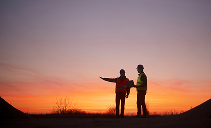 Two construction workers at sunset
